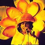 A man in a flower costume singing into a microphone.