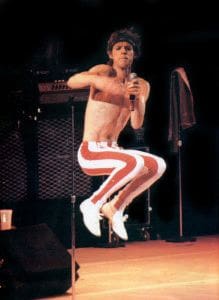 A man with red and white pants jumping in the air.