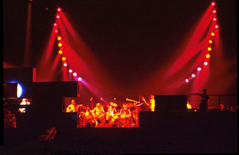 A band is playing on stage with red lights.